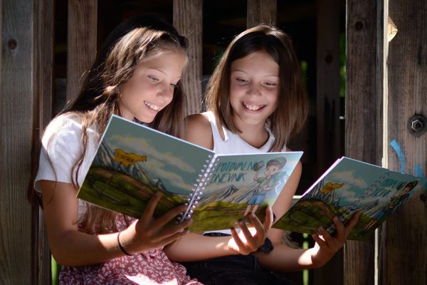 Dekleti bereta besedila Otroškega potovalnega dnevnika v lesni hišici na drevesu
